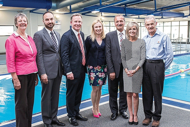 Seven people standing next to a pool.