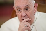 A close-up of Pope Francis with his finger on his chin.