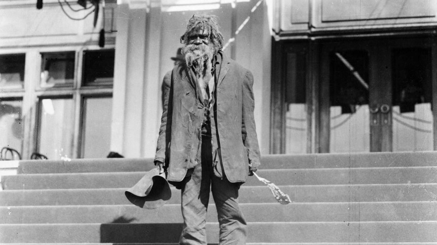 Indigenous man stands on steps outside Parliament House.
