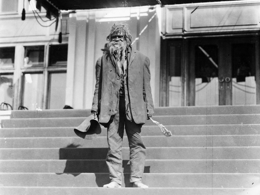 Indigenous man stands on steps outside Parliament House.