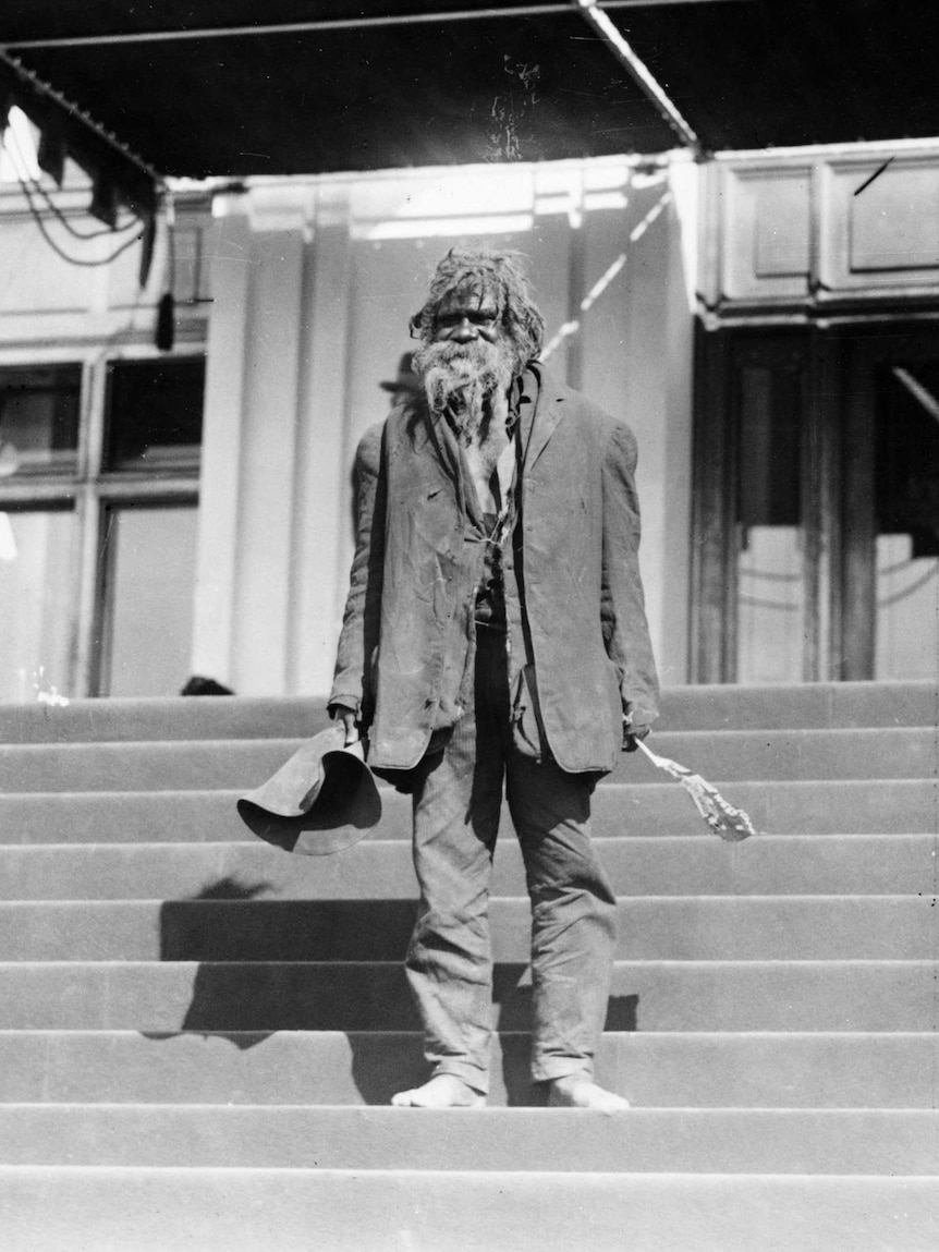 Indigenous man stands on steps outside Parliament House.