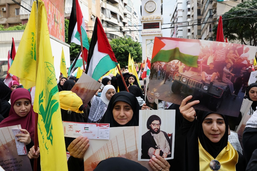 Women marching in the street holding flags and pictures of people