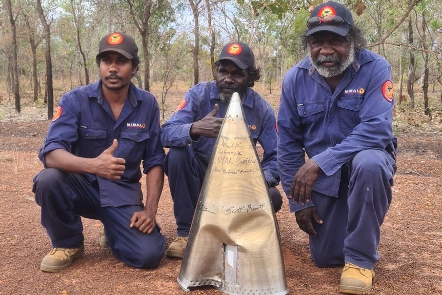 Three rangers with a piece of a rocket.