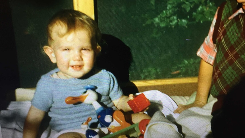 Baby Jol Fleming sitting with older brother surrounded by toys