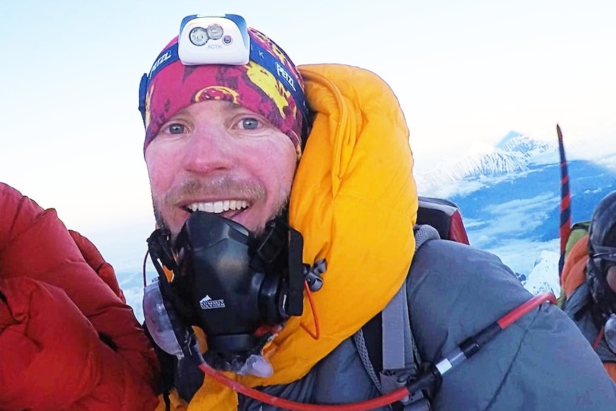 A man on a mountain smiling with cold weather gear