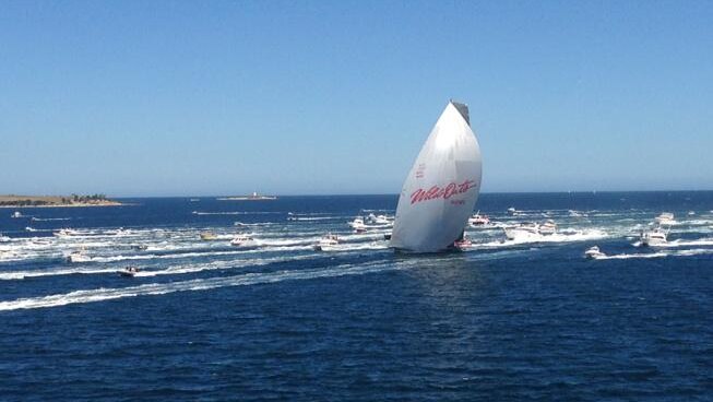 Wild Oats XI passes the Iron Pot surrounded by media and spectator boats