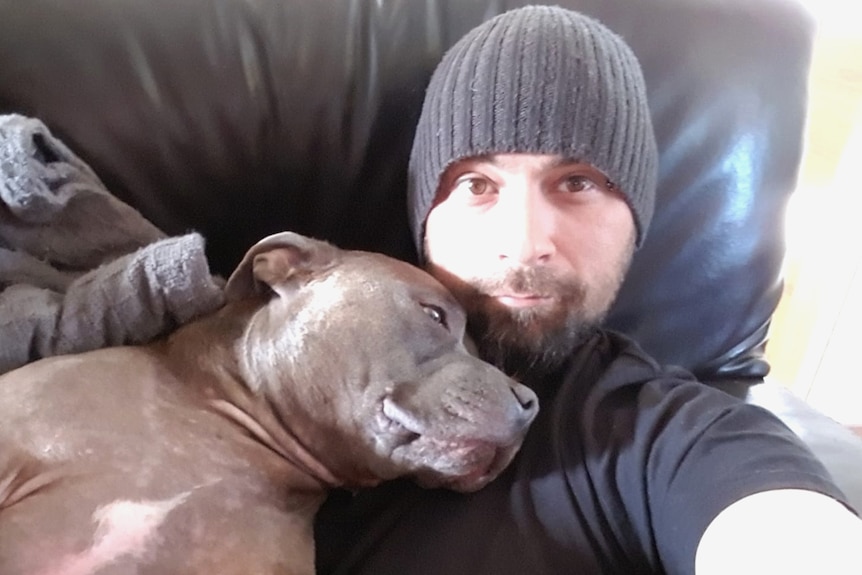 Kane Minion wearing a beanie with a dog sleeping on his chest