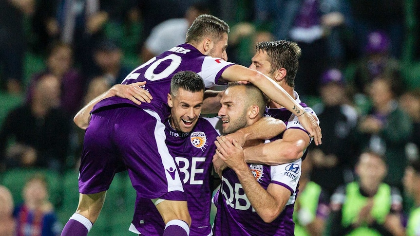 A group of Perth Glory players celebrate a goal.