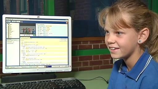 A young girl sits in front of a laptop computer