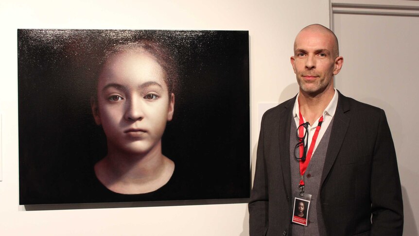Man standing next to painting of young girl