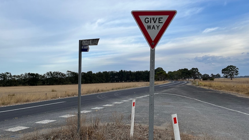 A "give way" sign at an intersection on a country road.