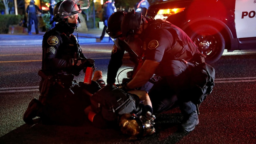 Police officers detain a demonstrator during a protest against police violence and racial injustice in Portland.