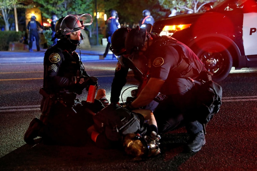 Police officers detain a demonstrator during a protest against police violence and racial injustice in Portland.