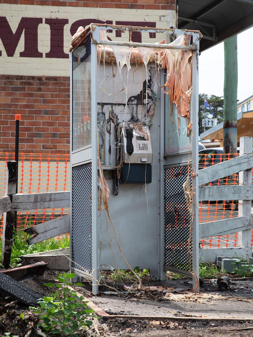 A phone booth so badly melted it looks as if it is hung with human skin.
