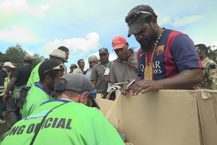 A polling official marks a ballot paper for a man at a polling booth at Purani village, Papua New Guinea