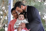 Tim Hammond kisses his baby son's head while standing alongside his wife.