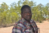 Aboriginal man stands in front of field