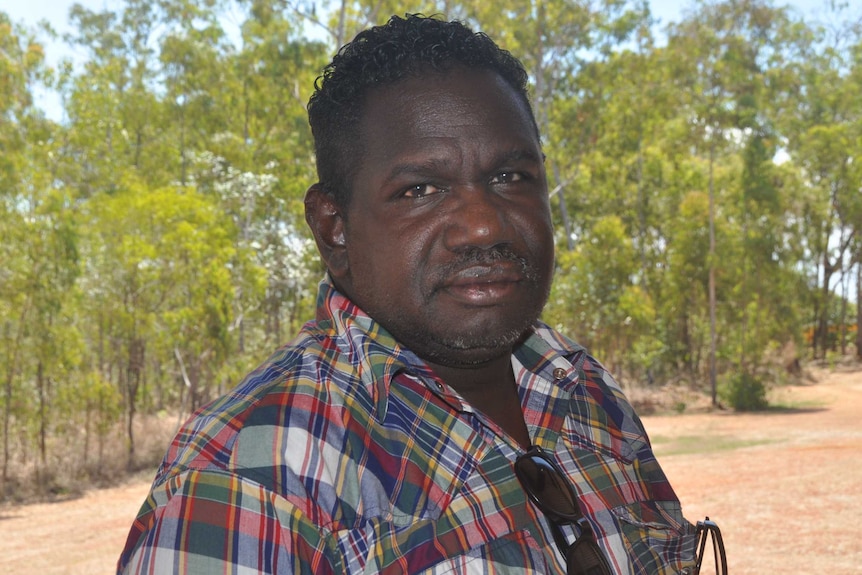 Aboriginal man stands in front of field