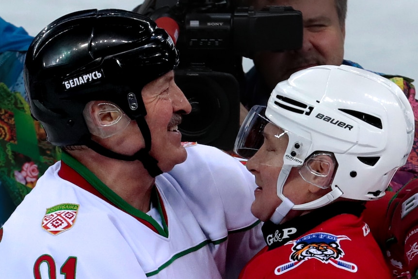 Vladimir Putin and Alexander Lukashenko embrace while wearing ice hockey outfits
