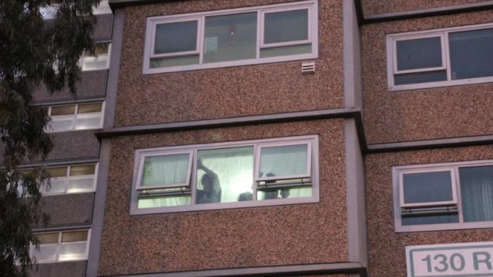 A person closing a curtain in a housing commission flat