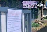A sign at the gate of the school alerting families to the COVID case.