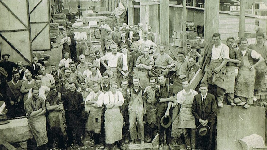 Black and white image of a large group of men in aprons.