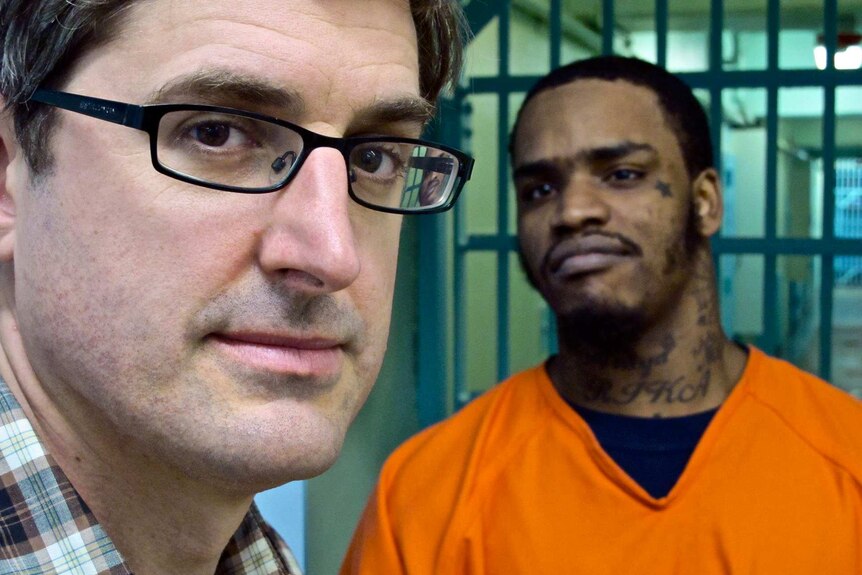 Louis Theroux standing with a prisoner in an orange prison suit