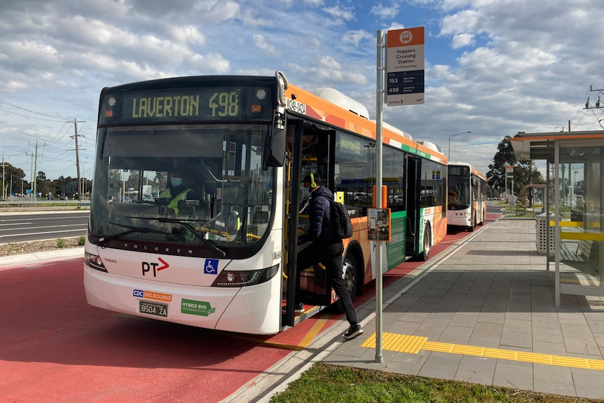 A man steps onto a bus that says it is Laverton-bound.