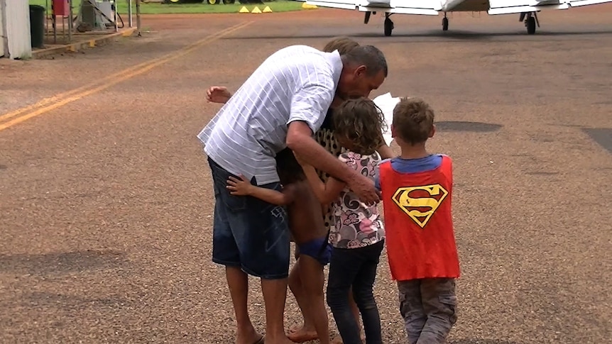Five children and their father hug after being rescued from a remote flooded road in the Kimberley.