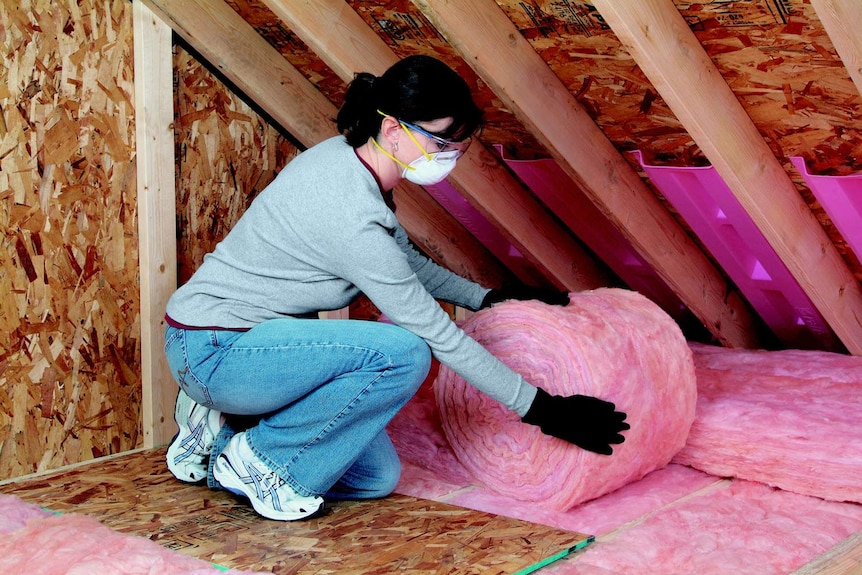 A woman installs pink roof insulation