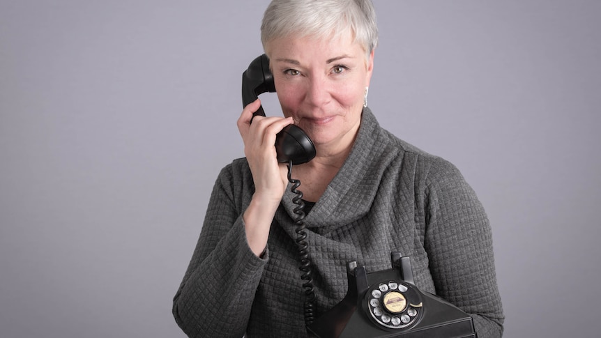 Mature aged lady with short grey hair holding a telephone receiver up to her ear