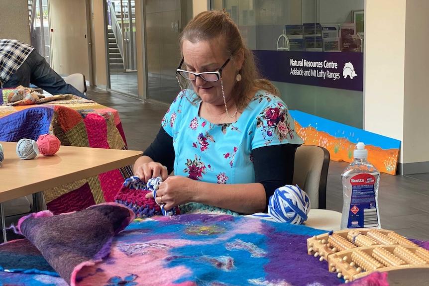 Abby Buckley crocheting at a table