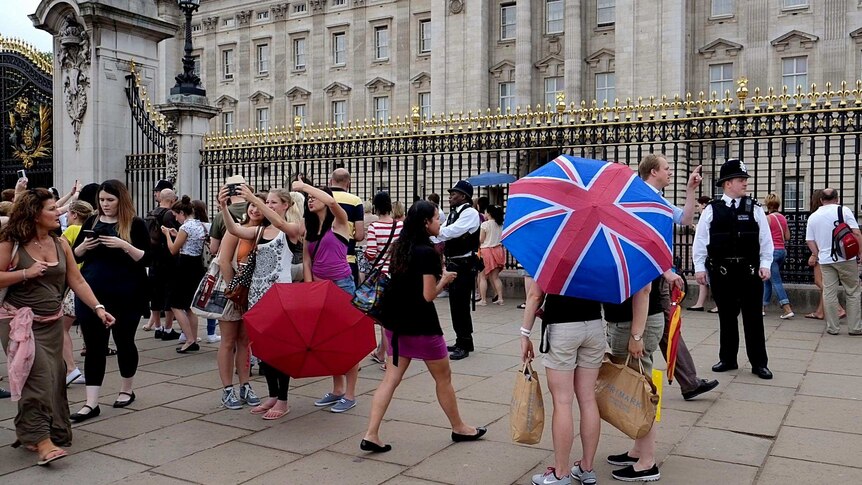 People mill around outside Buckingham Palace the day after the royal baby announcement.