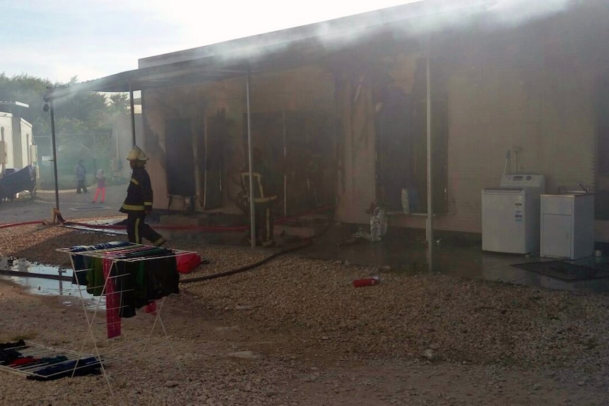 A refugee accommodation unit in Nauru damaged by fire in May 2016, firefighters are shown standing at the scene.