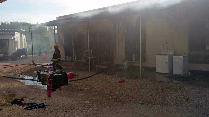 A refugee accommodation unit in Nauru damaged by fire in May 2016, firefighters are shown standing at the scene.