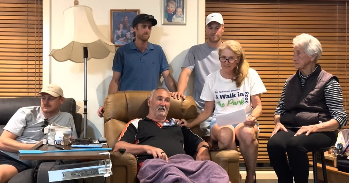 A man in a couch, with several family members nearby