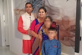 A man and a woman with a girl and a boy all in Indian costume in front of an artwork