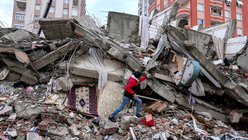 A man walks among rubble as he searches for people in a destroyed building in Adana.