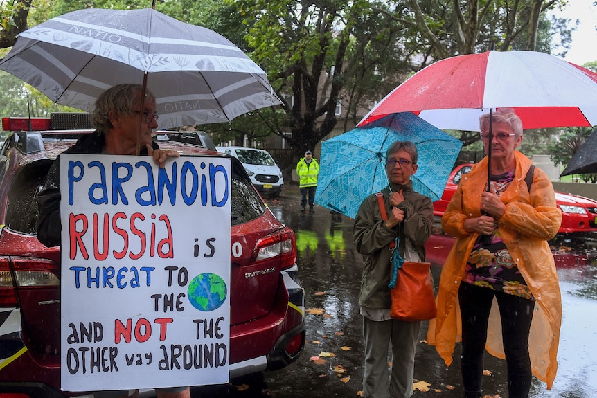 People hold signs in the rain