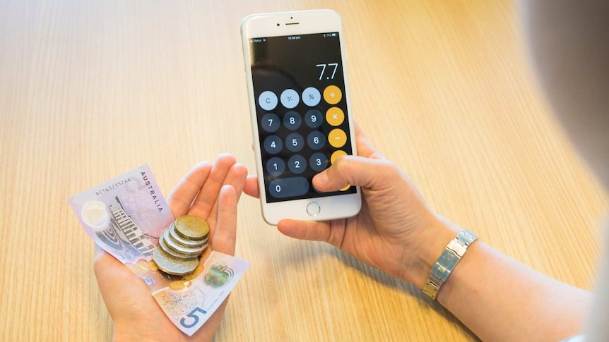 Woman holding a mobile phone and looking at money in her hand.