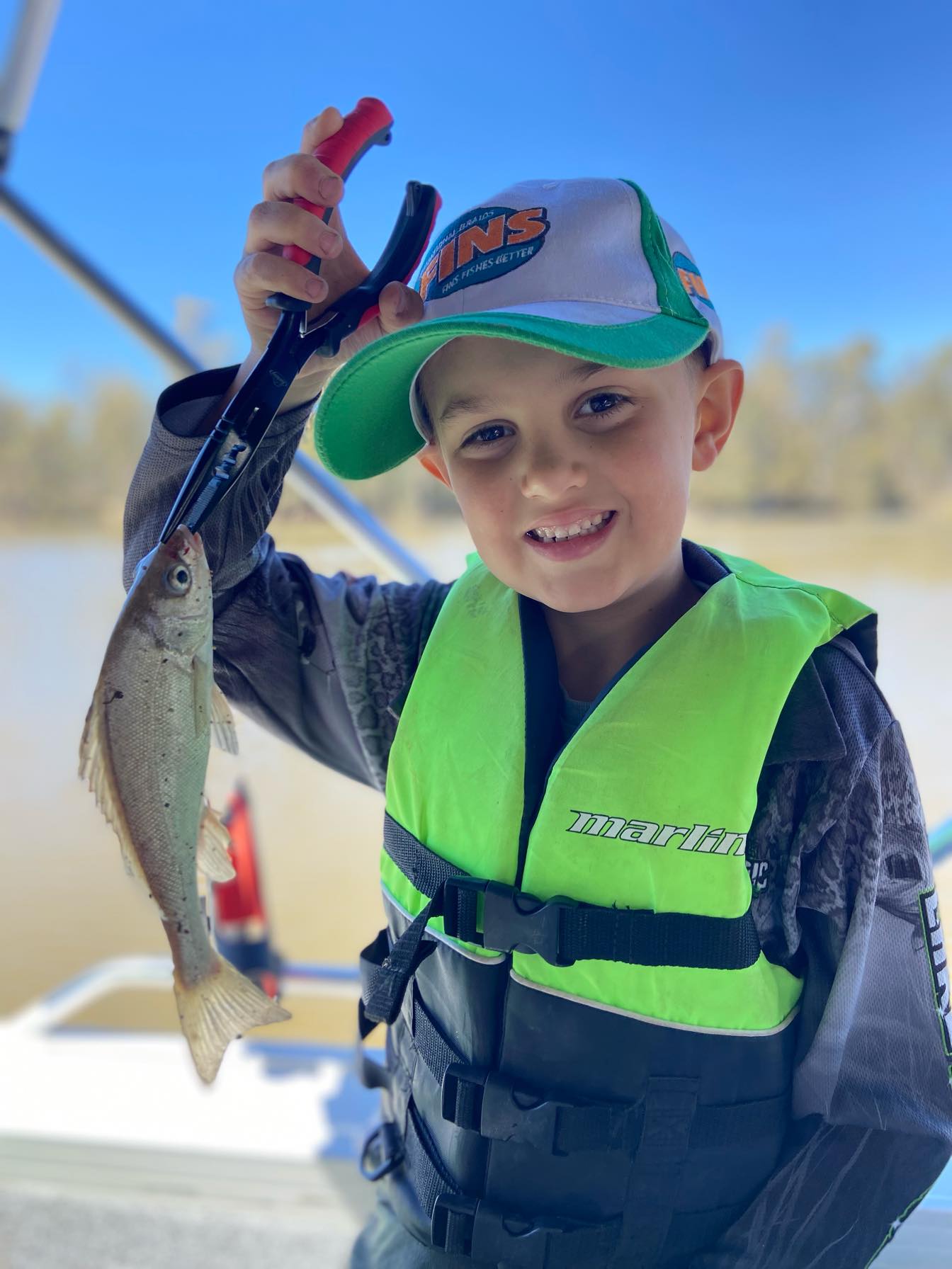 Boy holding fish on boat