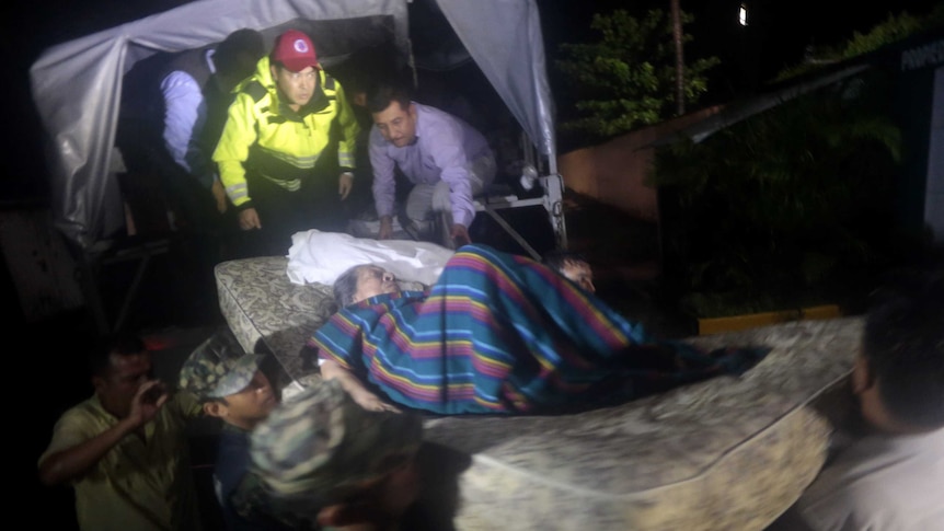 Mexican marines carry an elderly woman to a shelter