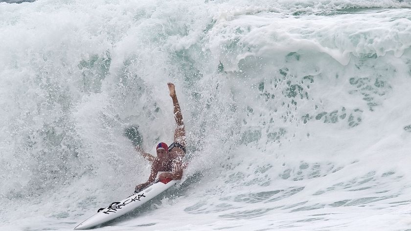 A competitor negotiates a huge wave during the board leg of the Open Ironman heats at Kurrawa on the Gold Coast.