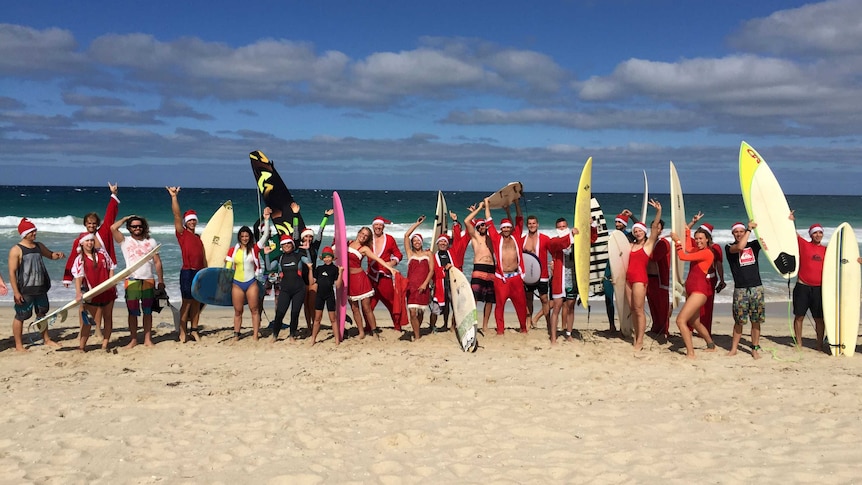 People dressed in Santa costumes holding surfboards on Scarborough Beach