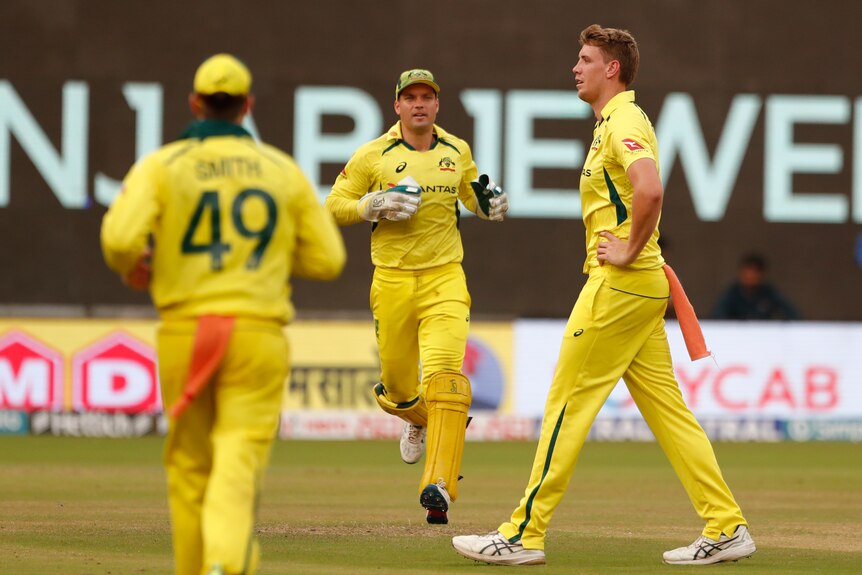 Australia bowler Cameron Green puts his hands on his hips as teammates Steve Smith and Alex Carey run towards him.