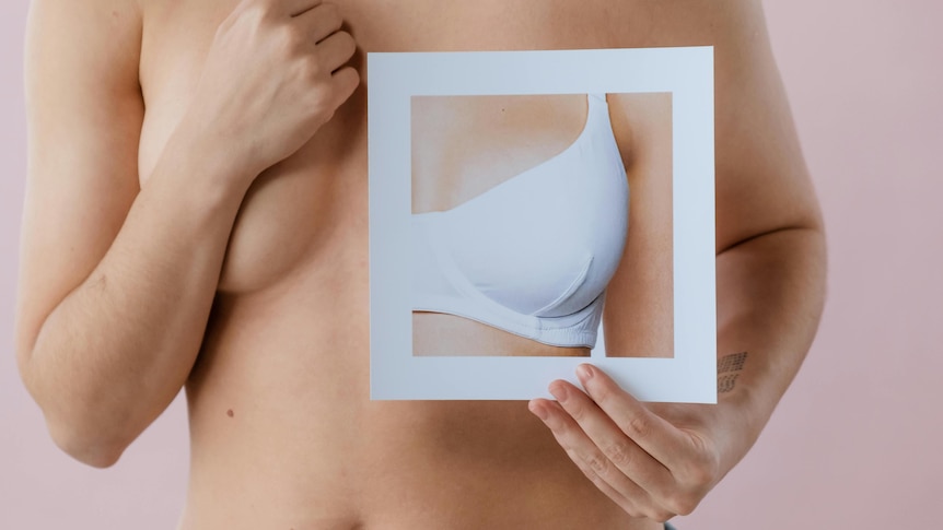 A generic image showing a woman holding up a photo of a breast in a bra to her bare chest.