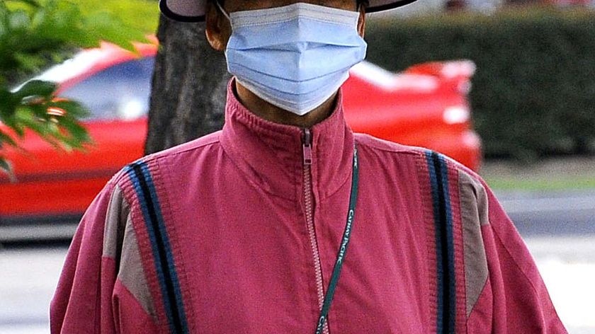 A woman walks along a street wearing a face mask
