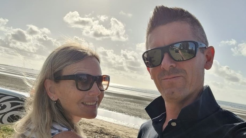 A man and woman taking a selfie on a beach.