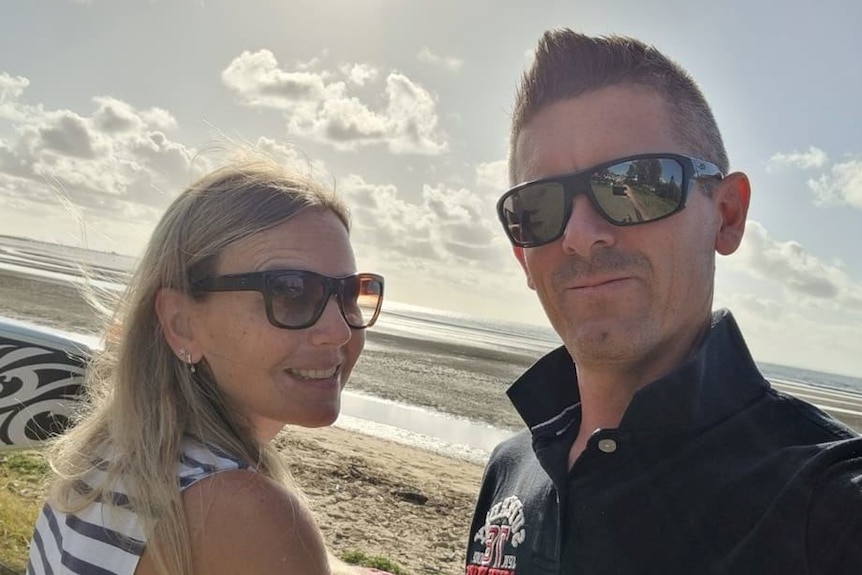 A man and woman taking a selfie on a beach.