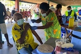 A woman holds a needle near a man's arm. Both are wearing surgical masks.